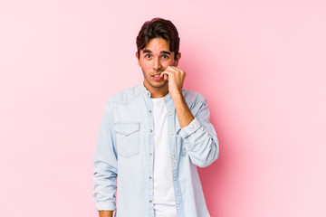 Young caucasian man posing in a pink background isolated biting fingernails, nervous and very anxious.