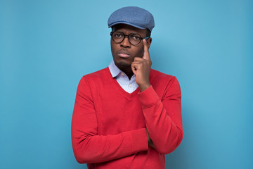 African man touching his chin, looking thoughtful and skeptical about something