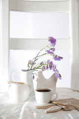 Festive table decoration for Easter. Coffee, milk jug and a bouquet of blue flowers in jug, as well as a bag with a gift in the shape of an Easter hare.
