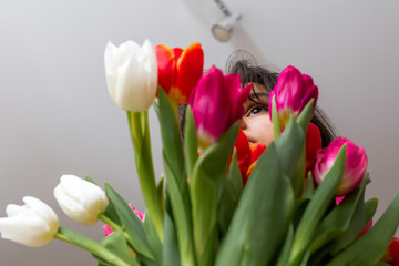 The girl's eye with highlights on the background of a blurred bouquet of tulips .