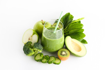 Freshly made green smoothie made of vegetables, fruits, herbs and greens. Glass of blended vegan beverage with ingredients around. Top view, close up, copy space, background.