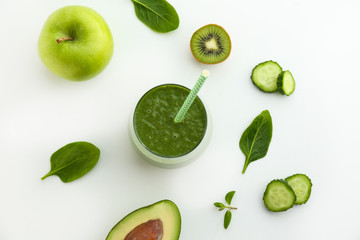 Freshly made green smoothie made of vegetables, fruits, herbs and greens. Glass of blended vegan beverage with ingredients around. Top view, close up, copy space, background.