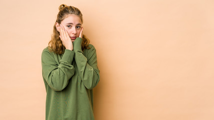 Young caucasian woman isolated on beige background scared and afraid.