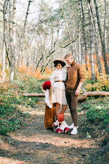happy family of four in the middle of a pine forest in the autumn, colorful foliage on the trees