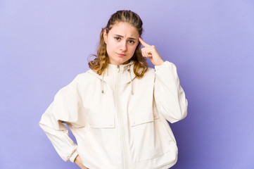 Young caucasian woman on purple background pointing temple with finger, thinking, focused on a task.