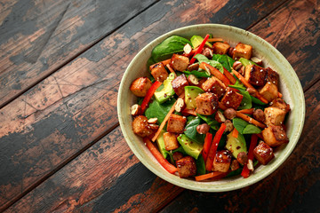 Healthy Vegan Fried Tofu salad with carrot, red bell pepper, spinach and nuts
