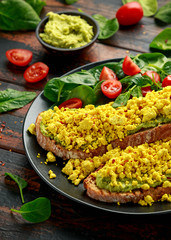Scrambled Tofu crispy Toast with guacamole and spinach, tomato salad. Vegan vegetarian, plant based food