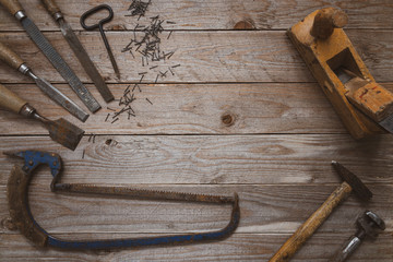Vintage woodworking tools on a wooden background. Chisels, raspers, plane, hammer, hand saw and...