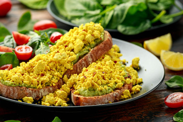 Scrambled Tofu crispy Toast with guacamole and spinach, tomato salad. Vegan vegetarian, plant based food