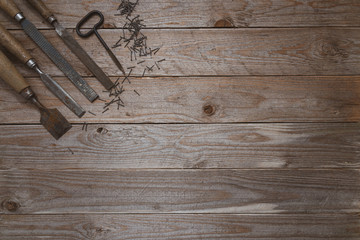 Vintage woodworking tools on a wooden background. Chisels, file, puncher and nails  neatly organized with a space copy opening. Carpentry, diy, craftsmanship concept, top view