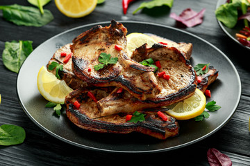 Homemade Grilled Pork loin chops in lemon sauce with herbs on rustic wooden table