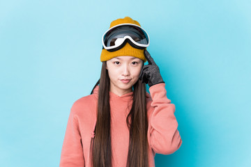 Young chinese woman wearing ski clothes isolated pointing temple with finger, thinking, focused on a task.