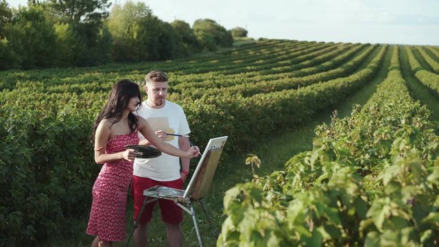 Beautiful couple of artists creatives a landscape and talks in bush field