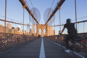 Brooklyn Bridge in a sunny morning with man cycling in New York.