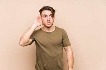 Young caucasian man posing isolated trying to listening a gossip.