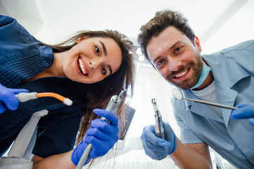 Portrait of a young female nurse and dentist doctor wearing a blue coat posing in a dentist office with medical equipment.