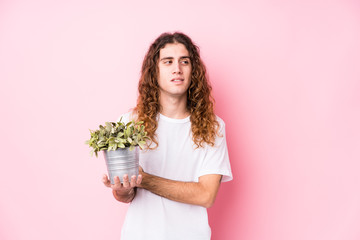 Long hair caucasian man holding a plant smiling confident with crossed arms.