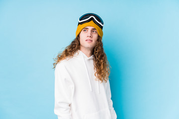 Young caucasian man wearing a ski clothes isolated  looks aside smiling, cheerful and pleasant.