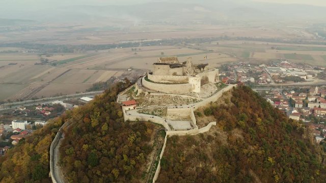 Aerial view of the Fortress Of Deva at sunset during fall.
Romanian flag on the Fortress Of Deva at sunset.