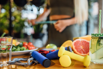 Fresh healthy food with dumbbells, jump rope, and excercise equipment on wood background top viwe with copy space. For dieting, fitness and active healthy lifestyles Concept