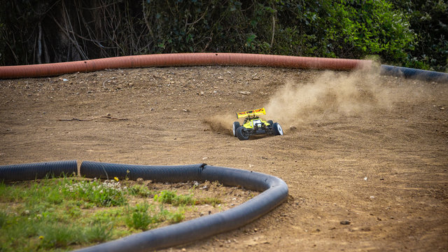 Yellow electric RC buggy drifting through a corner on an offroad outdoor track
