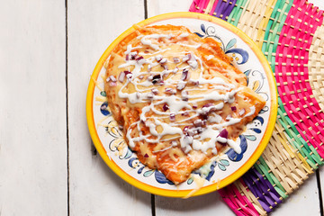 Mexican red enchiladas with melted cheese on white background
