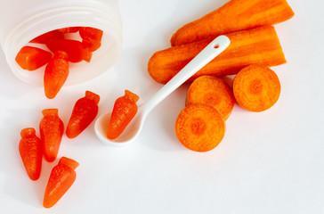 A bottle of gummy multivitamin with carrot on white background; top view of sprinkled chewing supplement
