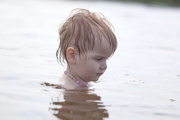 little independent girl sitting in the water on the lake
