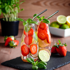 Refreshing drink or water with strawberry, citrus fruits lemon, lime and basil in mason jar with...