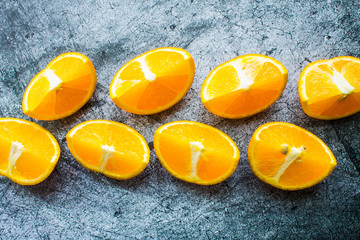 Fresh bright orange slices close up on a gray textured background