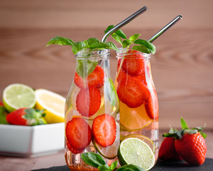 Refreshing drink or water with strawberry, citrus fruits lemon, lime and basil in mason jar with...