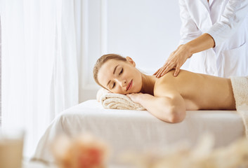 Obraz na płótnie Canvas Beautiful woman enjoying back massage with closed eyes. Spa treatment concept