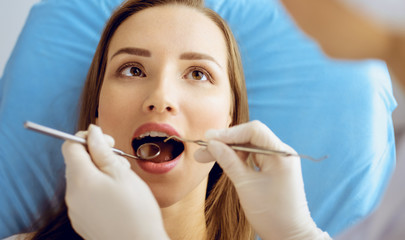 Smiling young woman with orthodontic brackets examined by dentist at dental clinic. Healthy teeth and medicine concept