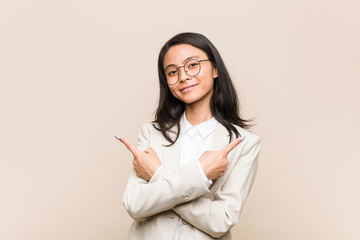 Young business chinese woman points sideways, is trying to choose between two options.