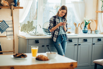 Smiling young lady texting while being at home stock photo