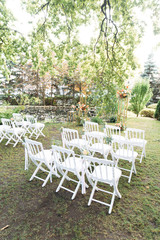 White wooden chairs in a row on the grass