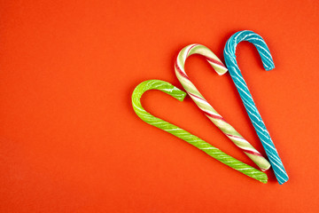 Traditional multi colored sweet Candy cane sticks with copy space minimal style still life on red background.