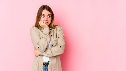 Young caucasian woman isolated on pink background biting fingernails, nervous and very anxious.