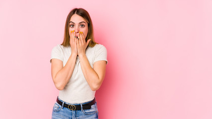 Young caucasian woman isolated on pink background shocked covering mouth with hands.