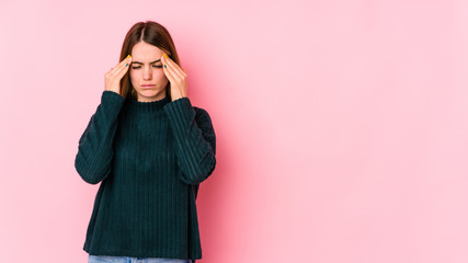 Obraz premium Young caucasian woman isolated on pink background having a head ache, touching front of the face.