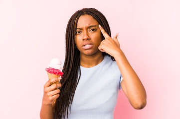 Young african american woman holding an ice cream isolated showing a disappointment gesture with forefinger.