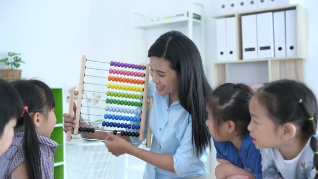Educational concepts. The teacher is teaching math with abacus for kindergarten children in the classroom, With a bright smiley face.