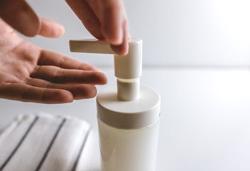 Woman washes hands, squeezes soap on the palm on a white background. Concept of protection against germs