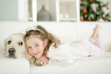 Cute little child with golden retriever dog enjoying Christmas atmosphere