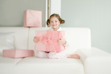 Cute child with Christmas gifts enjoying Christmas atmosphere