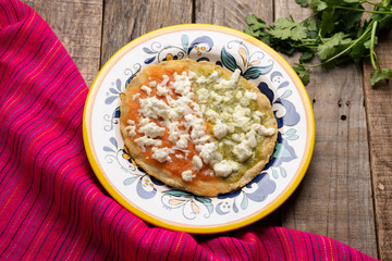 Mexican memela with green and red sauce on wooden background