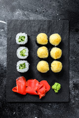 sushi rolls with cucumber, salmon and shrimp on a stone tray. Black background. Top view