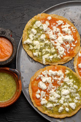 Mexican memela with green and red sauce on dark background