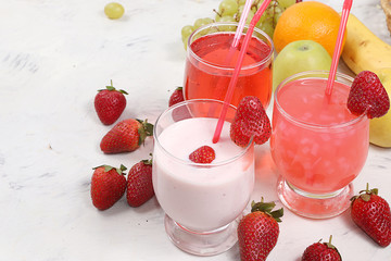 Strawberry smoothie, smoothie, juice or fruit drinks in glasses and ingredients on a sunny table....