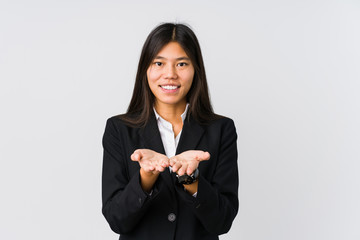 Young asian business woman holding something with palms, offering to camera.